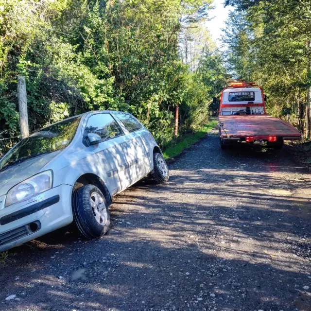 Grúa llegando a rescatar un auto pequeño a la orilla de un camino de tierra, a las afueras de Villarrica.